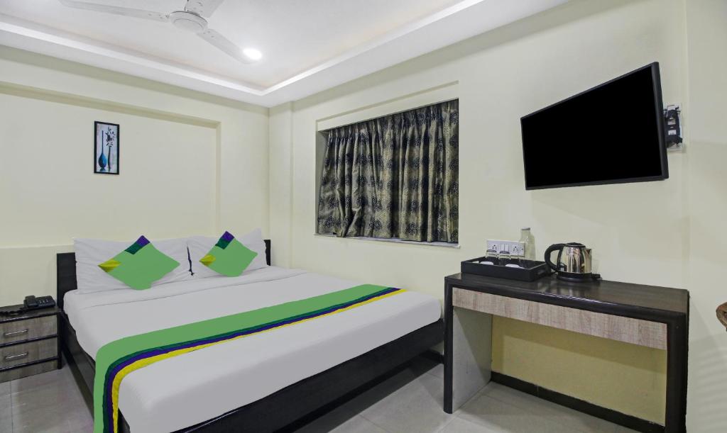 a bedroom with a bed and a desk and a television at Treebo Trend Naman's Inn in Kolkata