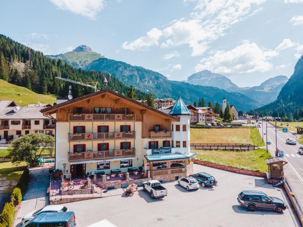 eine Stadt in den Bergen mit Autos auf einem Parkplatz in der Unterkunft Hotel Ciamol in Mazzin