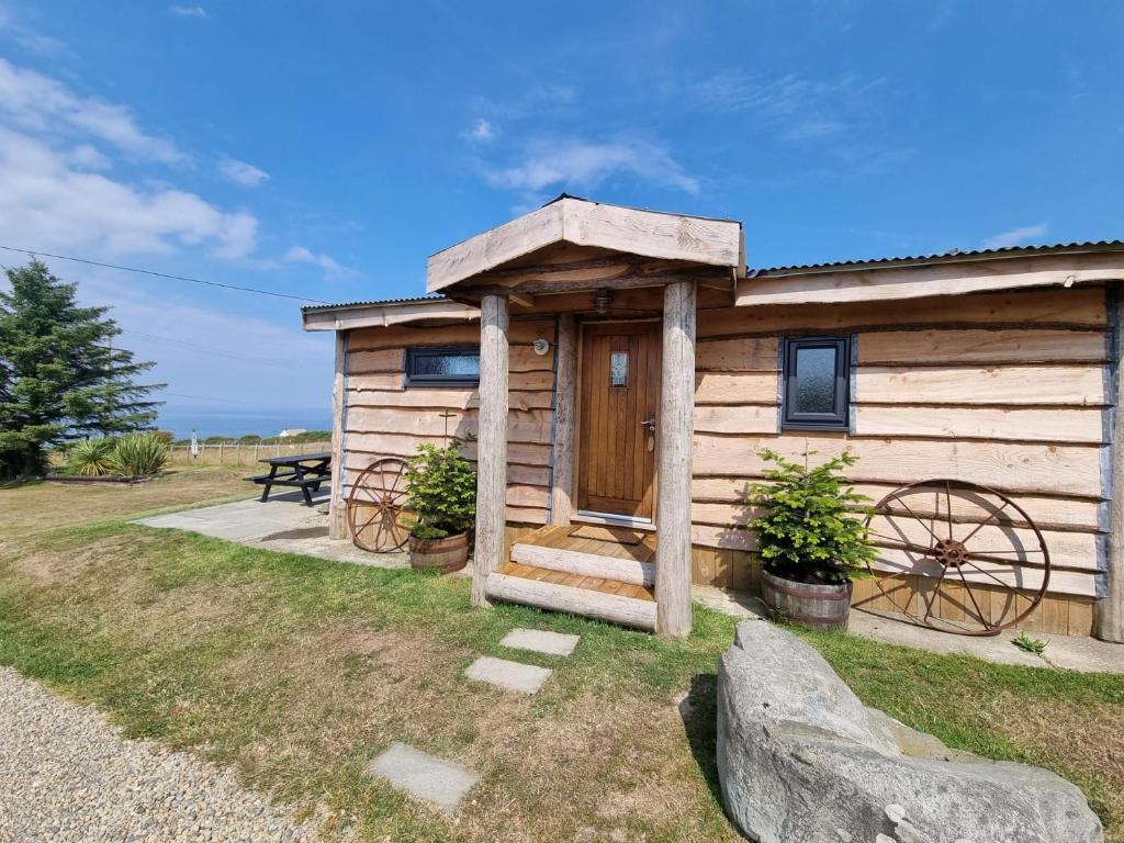 a wooden cabin with a wooden door and a bench at Byre Cottages & Log Cabin in Cardigan