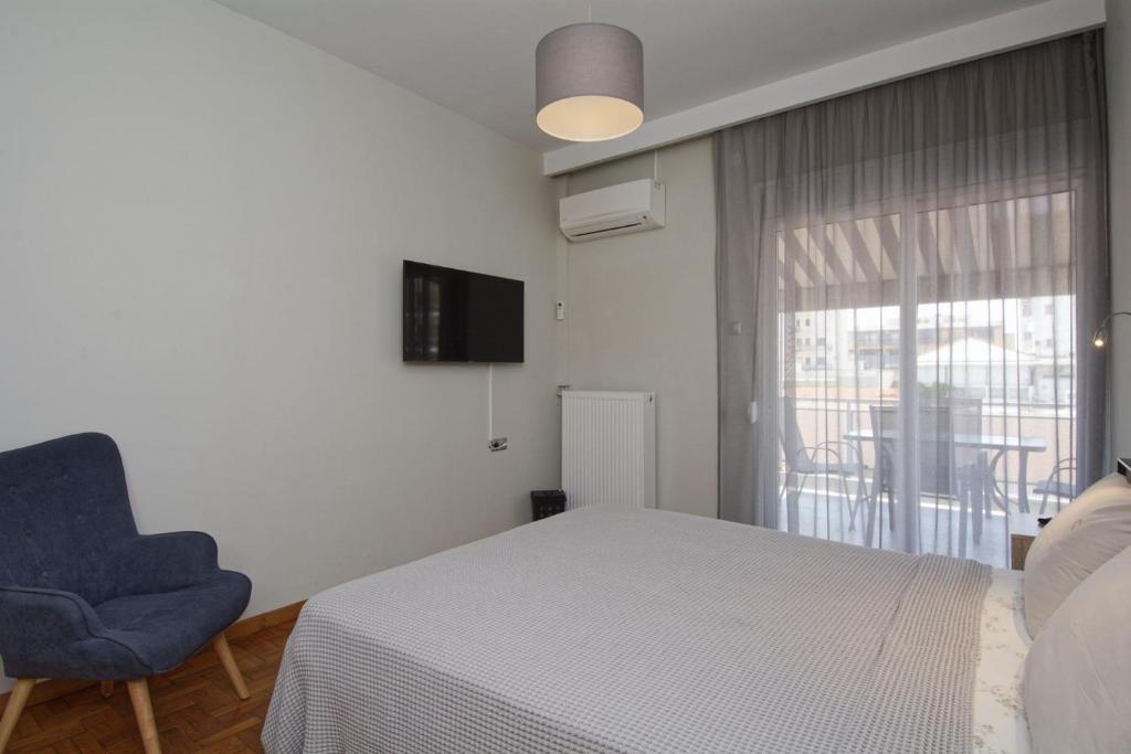 a bedroom with a bed and a chair and a window at MAHE APARTMENT in Volos