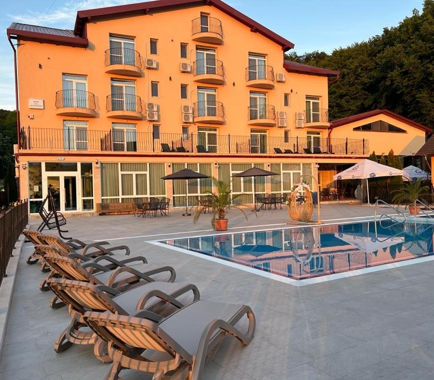 a hotel with chairs and a pool in front of a building at Metropol in Baile Felix