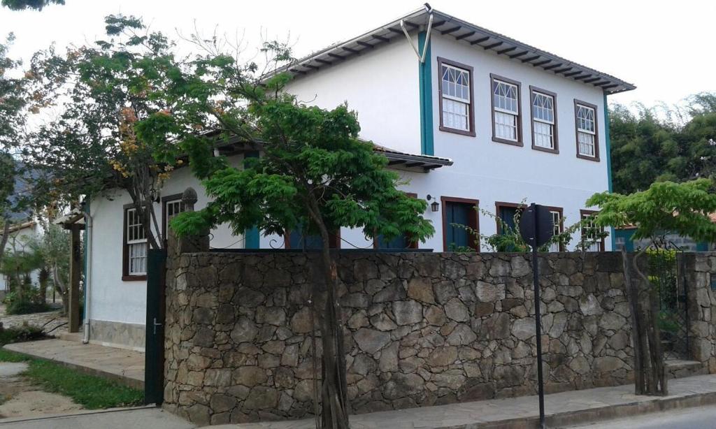 a white house behind a stone fence at Pouso Realeza in Tiradentes
