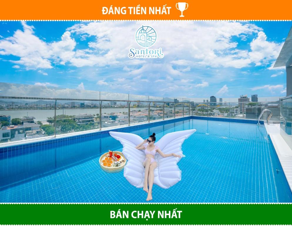 een vrouw verkleed als fee zittend op een zwembad bij Santori Hotel And Spa in Da Nang
