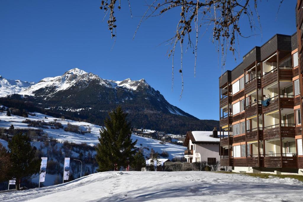 a building in the snow with a mountain in the background at Tgesa Sunnmatt 24 in Savognin