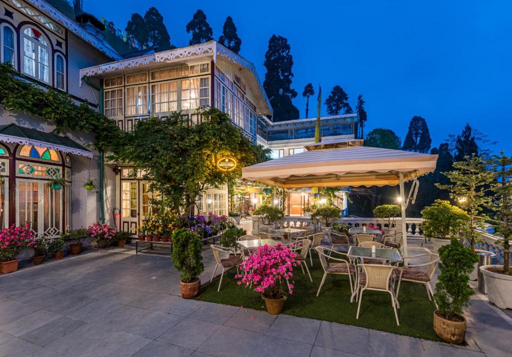 an outdoor patio with tables and chairs in front of a building at Udaan Dekeling Resort, Darjeeling in Darjeeling