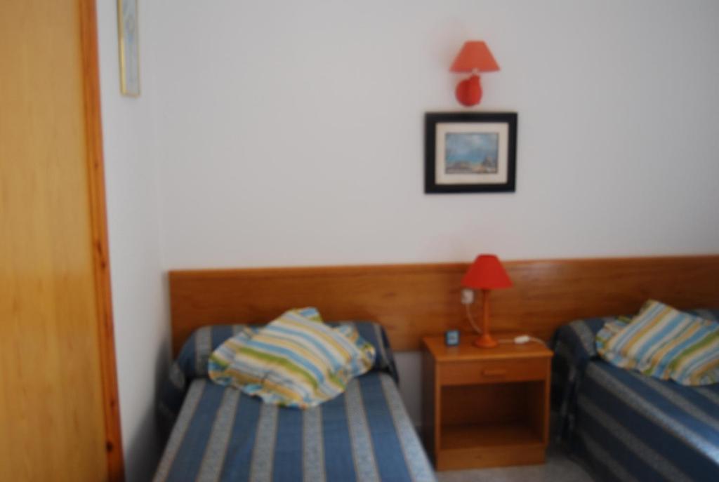 a bedroom with two beds and a table with a lamp at Es Pins in Cala Blanca