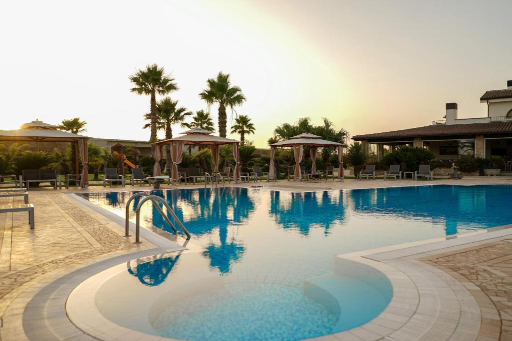 una piscina en un complejo con palmeras en el fondo en Ferrocino Resort, en Galatone