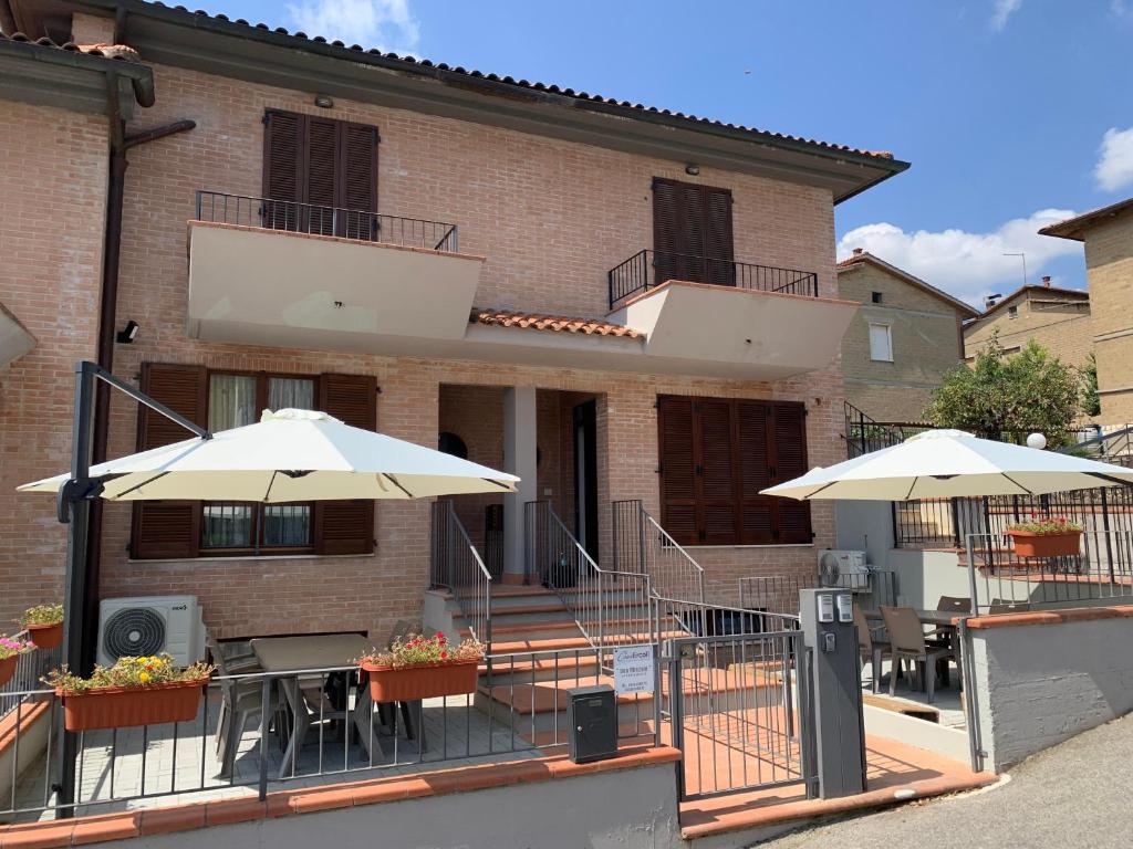 a building with tables and umbrellas in front of it at Casa Ercoli Abbadia in Abbadia di Montepulciano