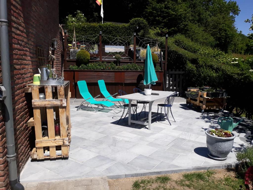 un patio con mesa, sillas y sombrilla en Studio Au jardin fleuri en Verviers