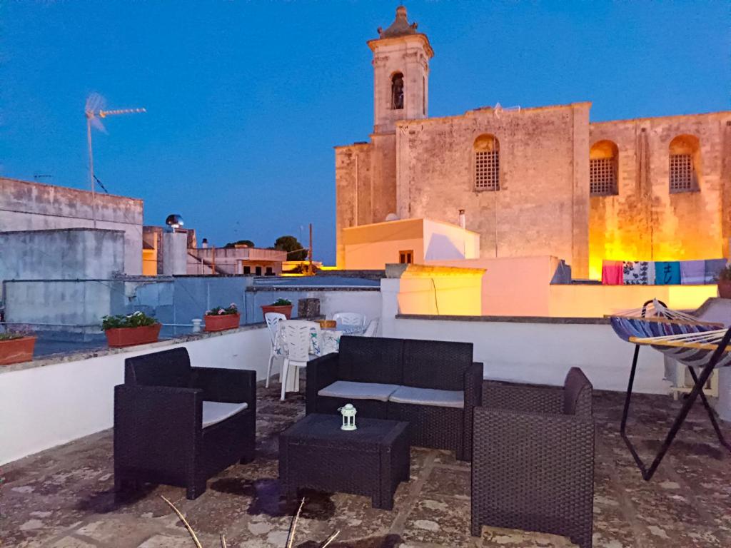 patio na dachu z krzesłami i stołami oraz budynek w obiekcie Casa vacanze Chiarodiluna w mieście Giurdignano