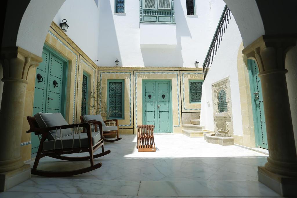 a hallway with green doors and chairs in a building at Dar Hammamet Guest House & Hammam in Hammamet