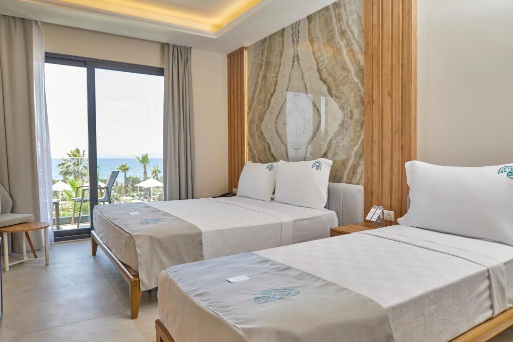 two beds in a hotel room with a view of the ocean at Rammos Managed By Dedeman in Bodrum City