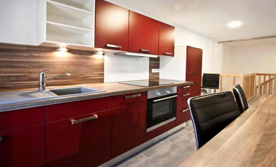 a kitchen with red cabinets and a sink and a table at Appartements Le Hupsa Pfannala in Saint-Hippolyte