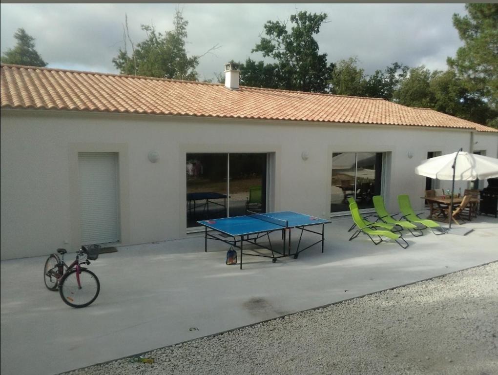 une terrasse avec une table, des chaises et un parasol dans l'établissement Spacieuse villa, aux Mathes