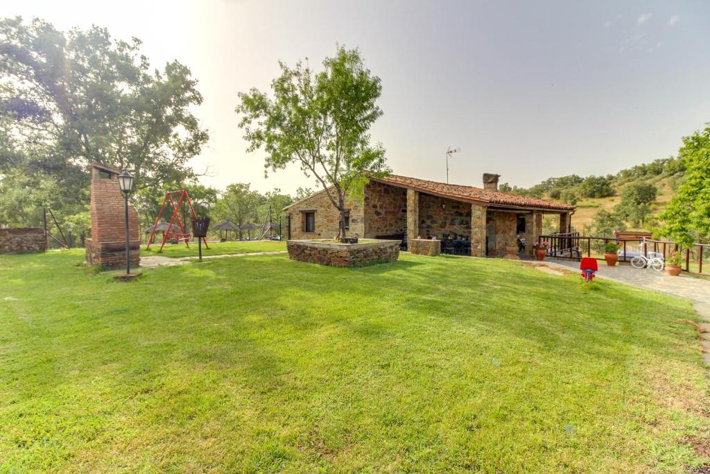 una casa con un gran patio con parque infantil en Casa Rural Manantío Blanco, en Valverde del Fresno