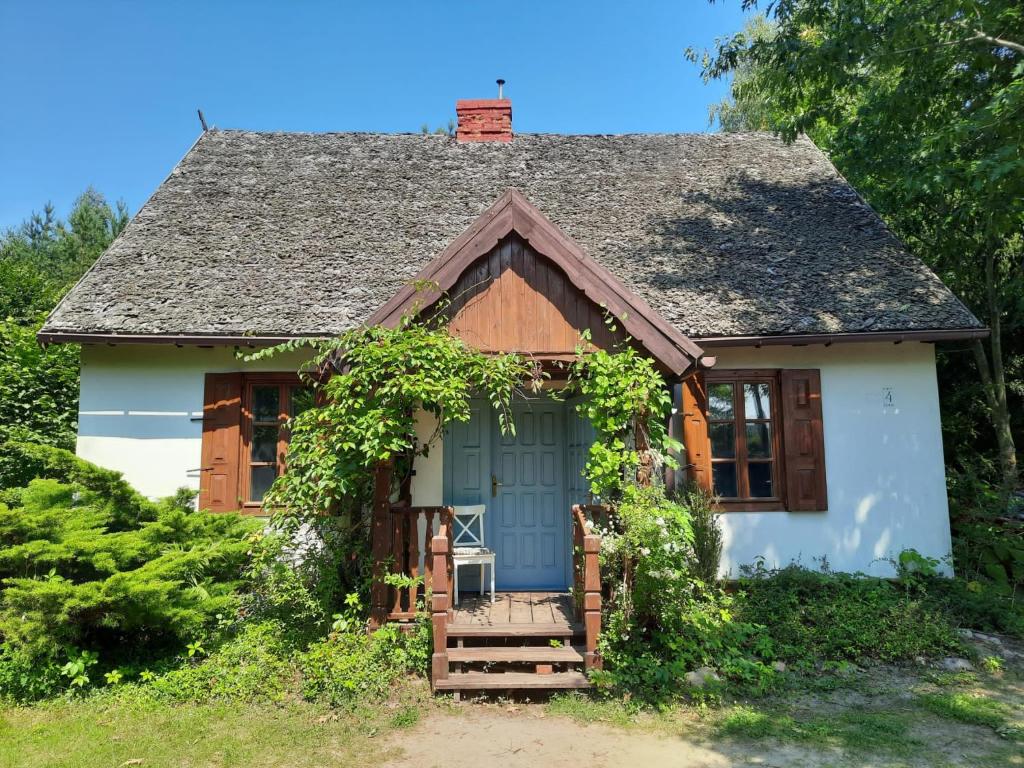 a small white house with a blue door at AŻ POD LAS in Zbiczno