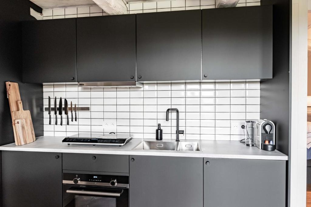 a kitchen with black cabinets and a sink at MAISON de la Bonne Vie in Thérondels