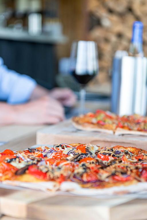 two pizzas sitting on a table with a glass of wine at MAISON de la Bonne Vie in Thérondels