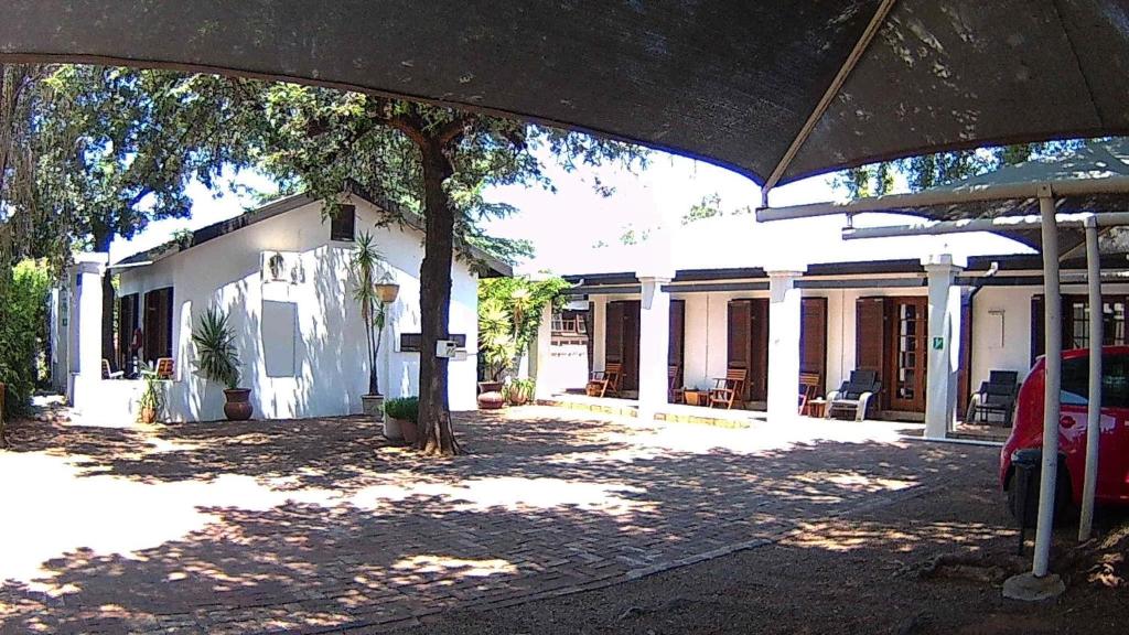 a white house with a tree in front of it at Kuru-Kuru Guesthouse in Kuruman