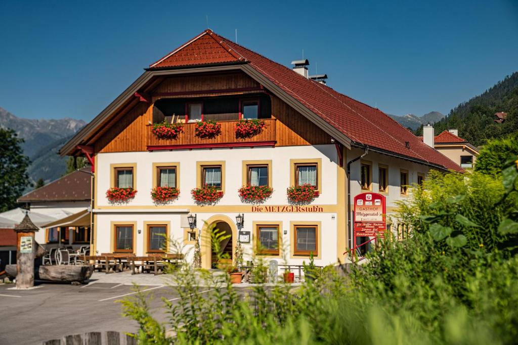 ein weißes Gebäude mit rotem Dach und Blumen darauf in der Unterkunft Hotel Die Metzgerstubn in Sankt Michael im Lungau