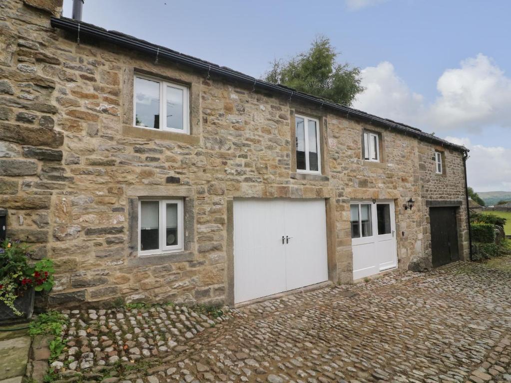 a stone house with two white garage doors at Darrowby Barn in Skipton