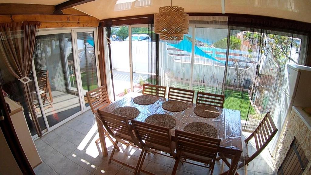a dining room with a table and chairs and windows at Les margouillats - maisonnette à 2 pas de la plage in Vias