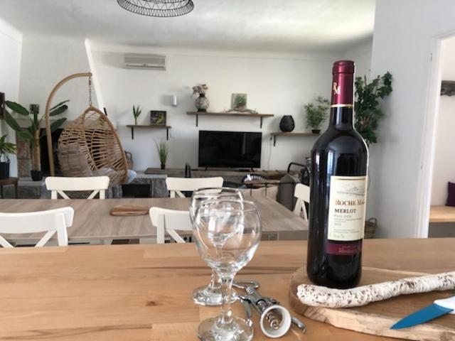 a bottle of wine sitting on a table with a wine glass at Grande maison de caractere situee au cœur du village de de Roquefort des Corbières. Profitez de son grand jardin avec terrain de petanque barbecue et balancoire in Roquefort-des-Corbières