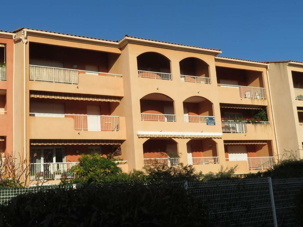 un immeuble d'appartements avec des balcons sur le côté dans l'établissement Spacieux T2 avec Loggia à 800m de la Plage, Parking et Forfait Ménage Inclus - Bormes-les-Mimosas - FR-1-610-12, à Bormes-les-Mimosas