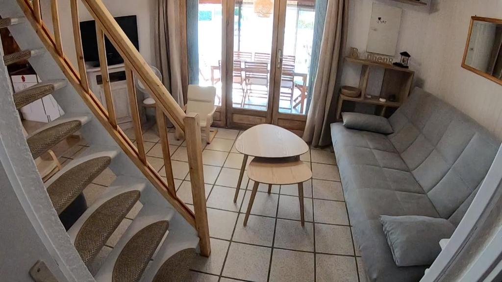 a living room with a staircase and a table and chairs at Les margouillats - maisonnette à 2 pas de la plage in Vias
