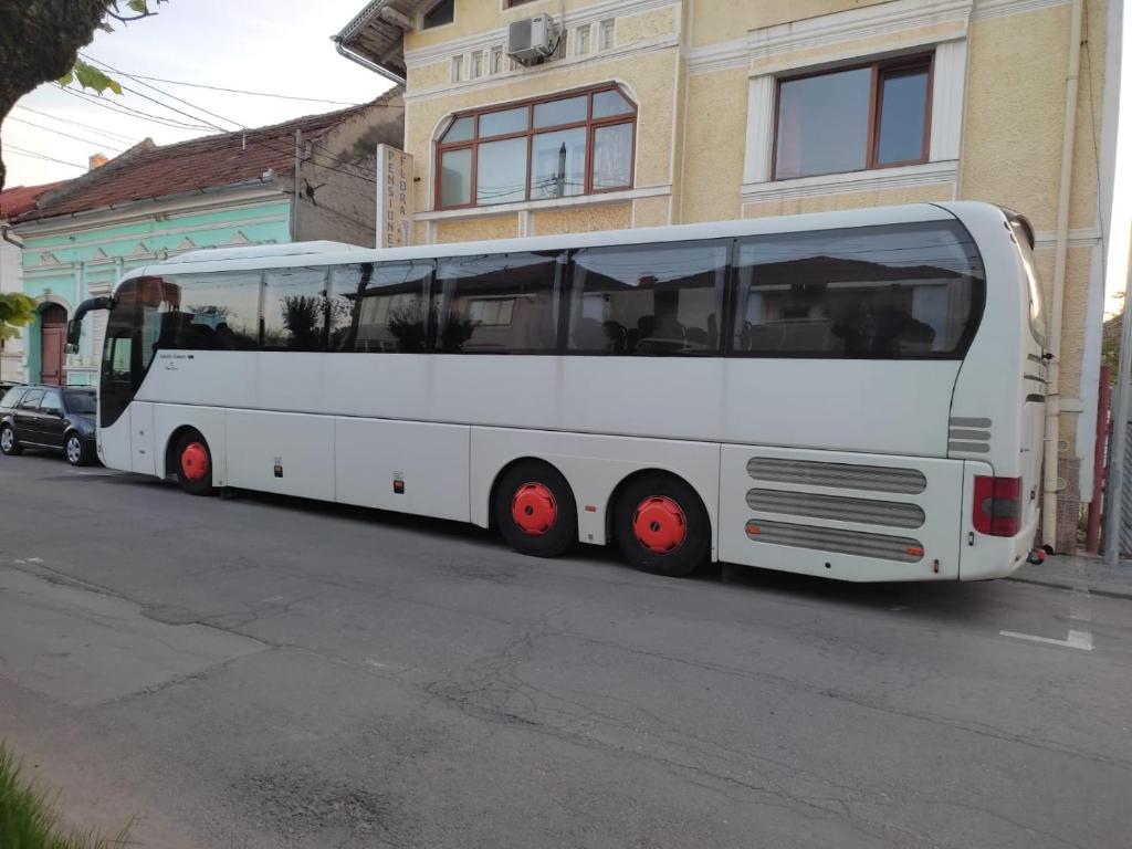 a white bus parked on the side of a street at Casa Drumețului in Făgăraş