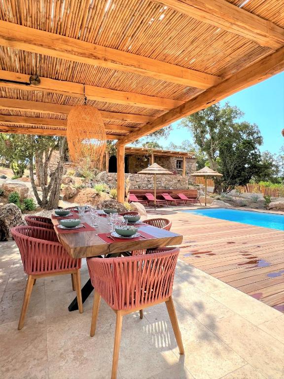 une table et des chaises en bois sous une pergola en bois dans l'établissement Casetta Tinuta, à Sainte-Lucie de Porto-Vecchio