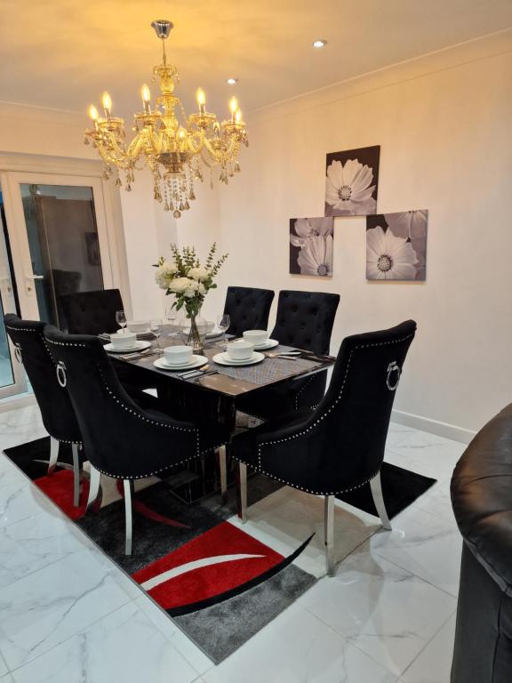 a dining room table with black chairs and a chandelier at Linx View 4 Bedroom House in Kent