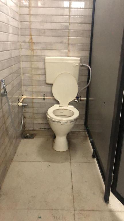 a bathroom with a white toilet in a stall at Charyana Backpackers in Ahmedabad