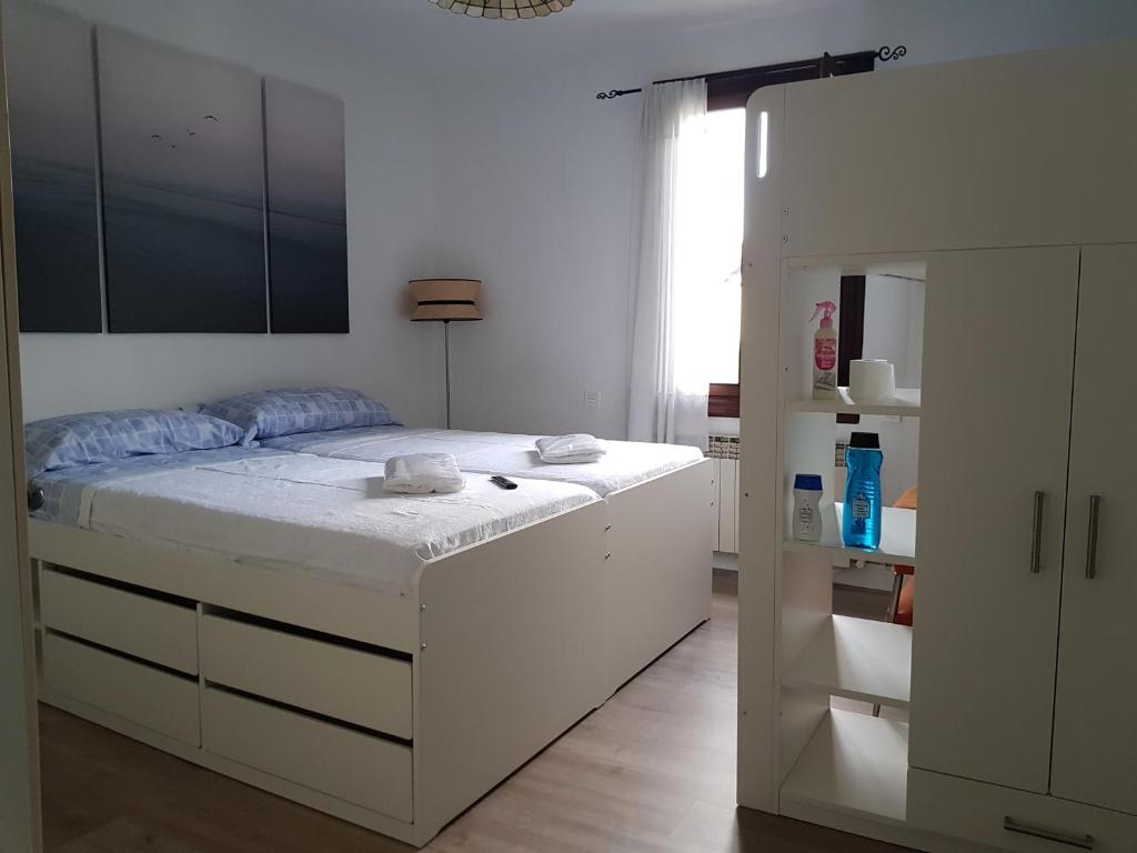 Un dormitorio blanco con una cama grande y una ventana en TUUL ETXEA, Habitación en caserío a 8km de Bilbao, Baño compartido en Galdakao