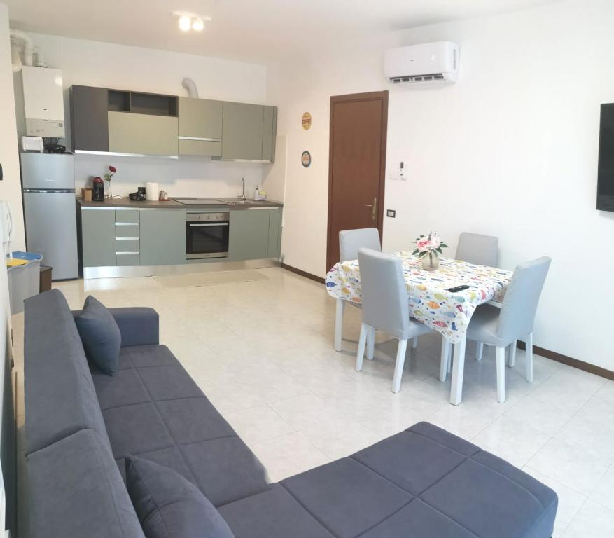 a living room with a couch and a table with chairs at Rosolina (Paese) Apartment in Rosolina