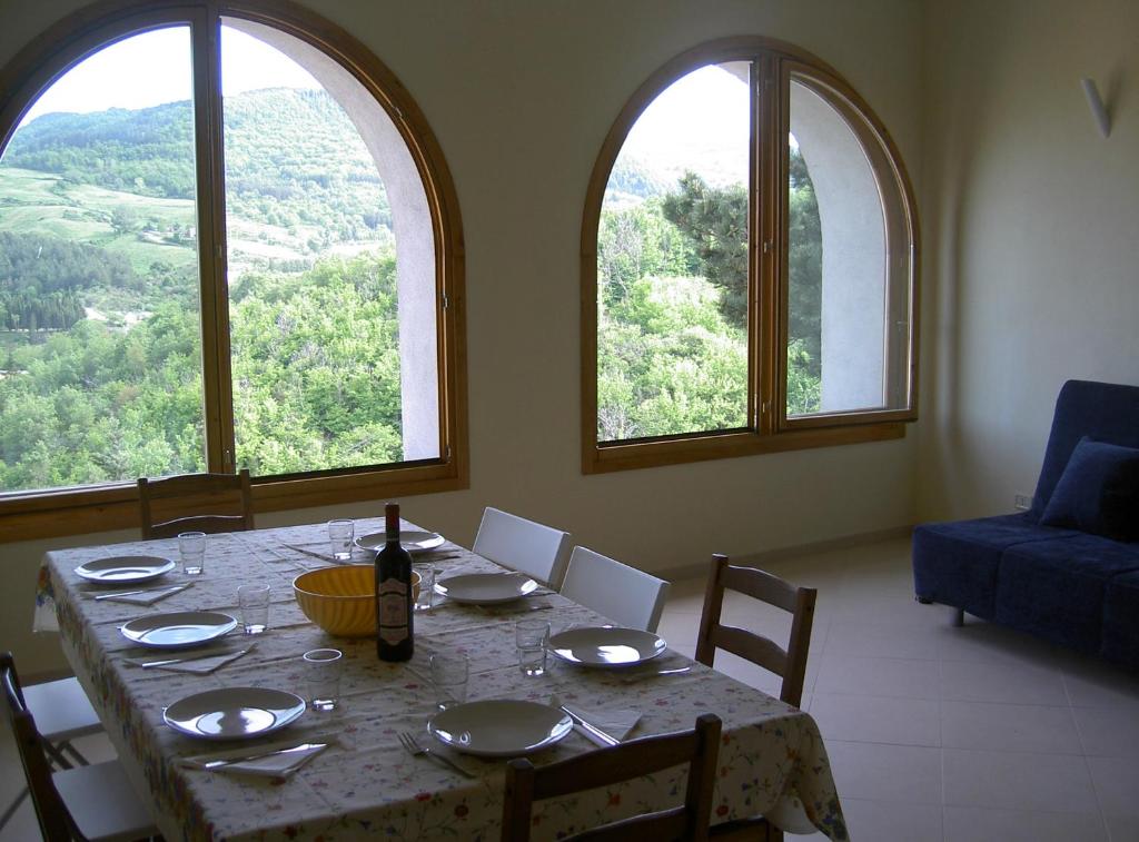 una sala da pranzo con tavolo e due grandi finestre di CASA IN MAREMMA TOSCANA a Monticello
