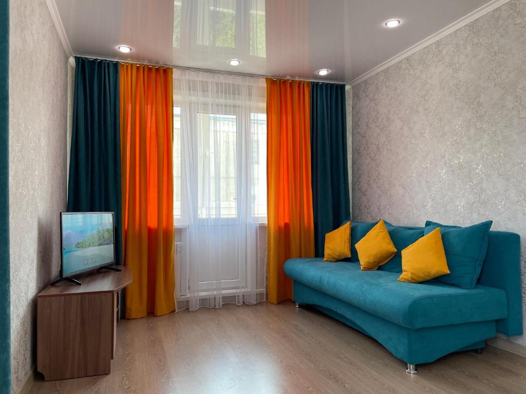 a living room with a blue couch and a television at Квартира целиком с двуспальной кроватью и белым постельным in Petropavlovsk
