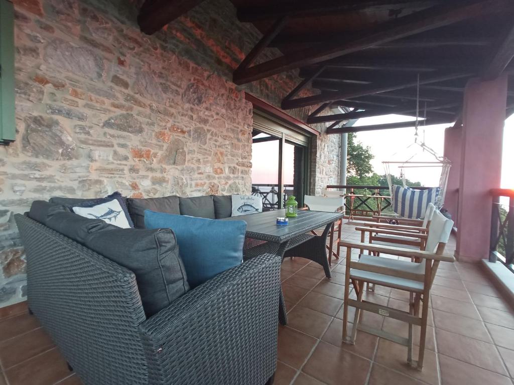 un patio con sofá, mesa y sillas en Villa Sklithro in the heart of the forest with magnificent view of the sea just 10 minutes from it, en AgiaKampos