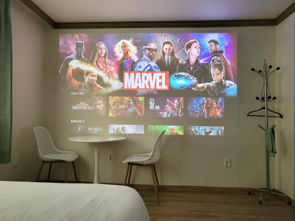 a bedroom with a large poster of marvel movies on the wall at Top Island Hotel in Jeju
