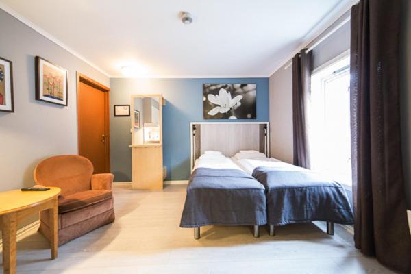 a bedroom with a bed and a chair and a table at Pensjonat Jarlen in Trondheim