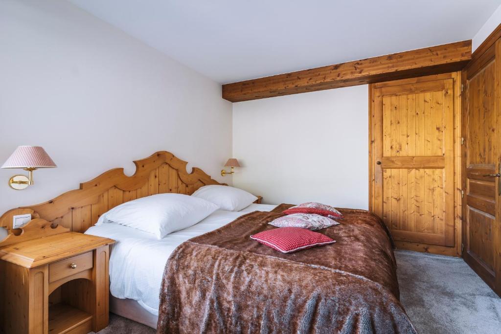 a bedroom with a large bed with a wooden headboard at Hôtel Les Peupliers in Courchevel