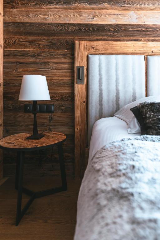 a bedroom with a bed and a table with a lamp at Hôtel Les Peupliers in Courchevel