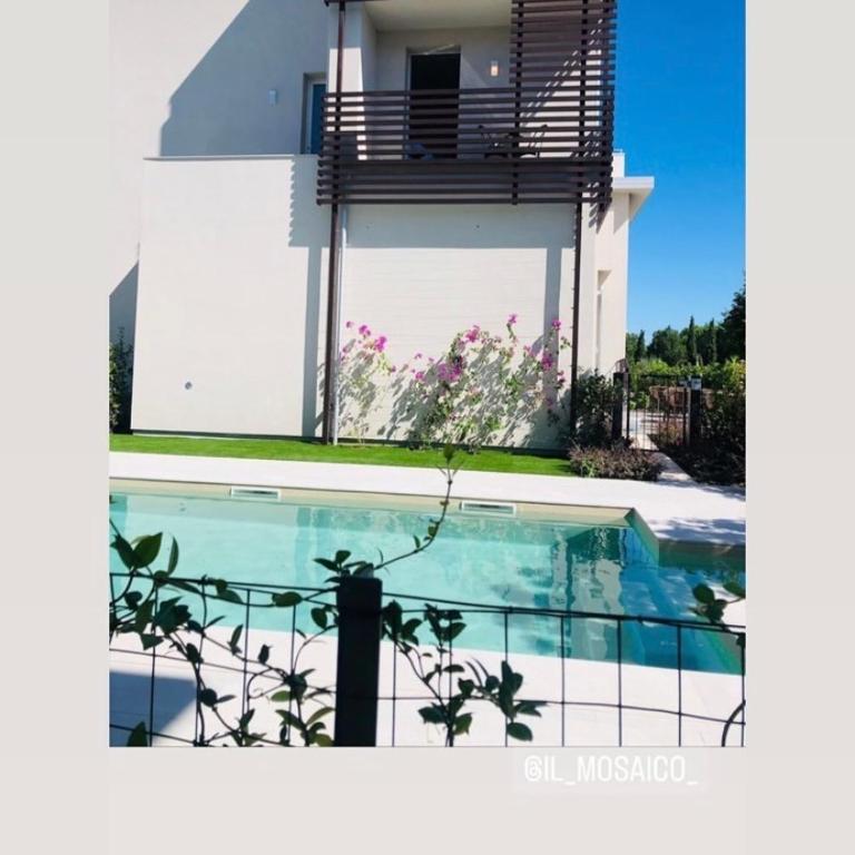 a house with a swimming pool in front of a building at Hotel B&B il Mosaico in Sirmione