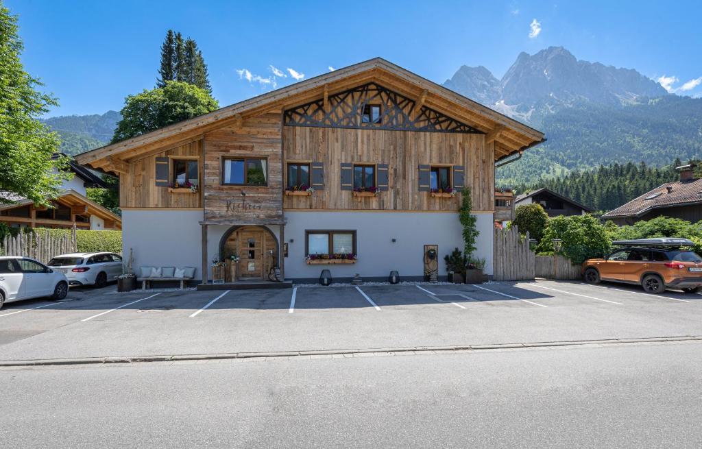 ein großes Holzgebäude mit Autos auf einem Parkplatz in der Unterkunft Gästehaus Richter in Grainau