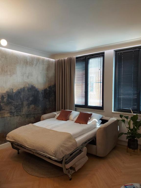 a bedroom with a large bed and two windows at Apartament Zamojski Rynek in Zamość