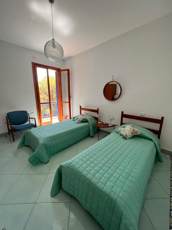 a bedroom with two beds and a chair and a window at A casa di Ludo in Montecorice