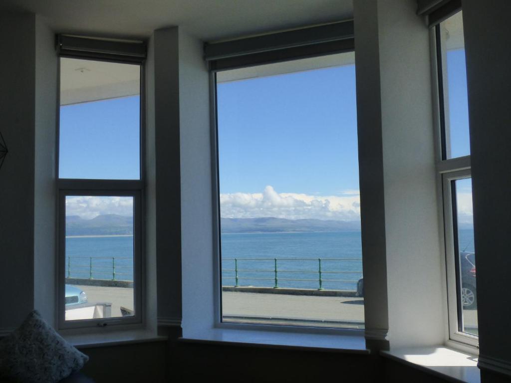 a room with three windows with a view of the ocean at Cadair Idris in Criccieth