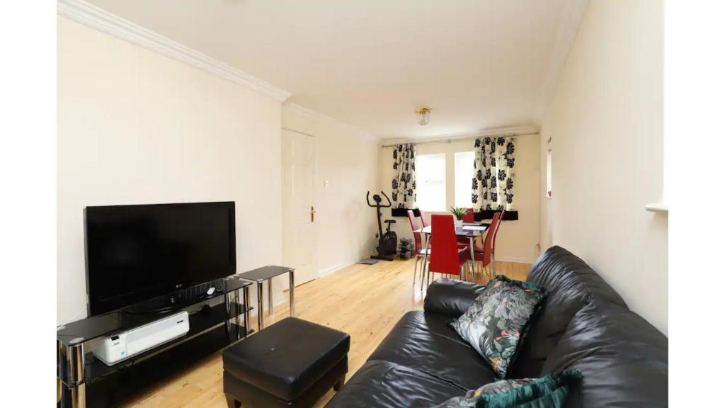 a living room with a black leather couch and a flat screen tv at Pass the Keys Central Oxford 2 Bed Apartment with Parking in Oxford