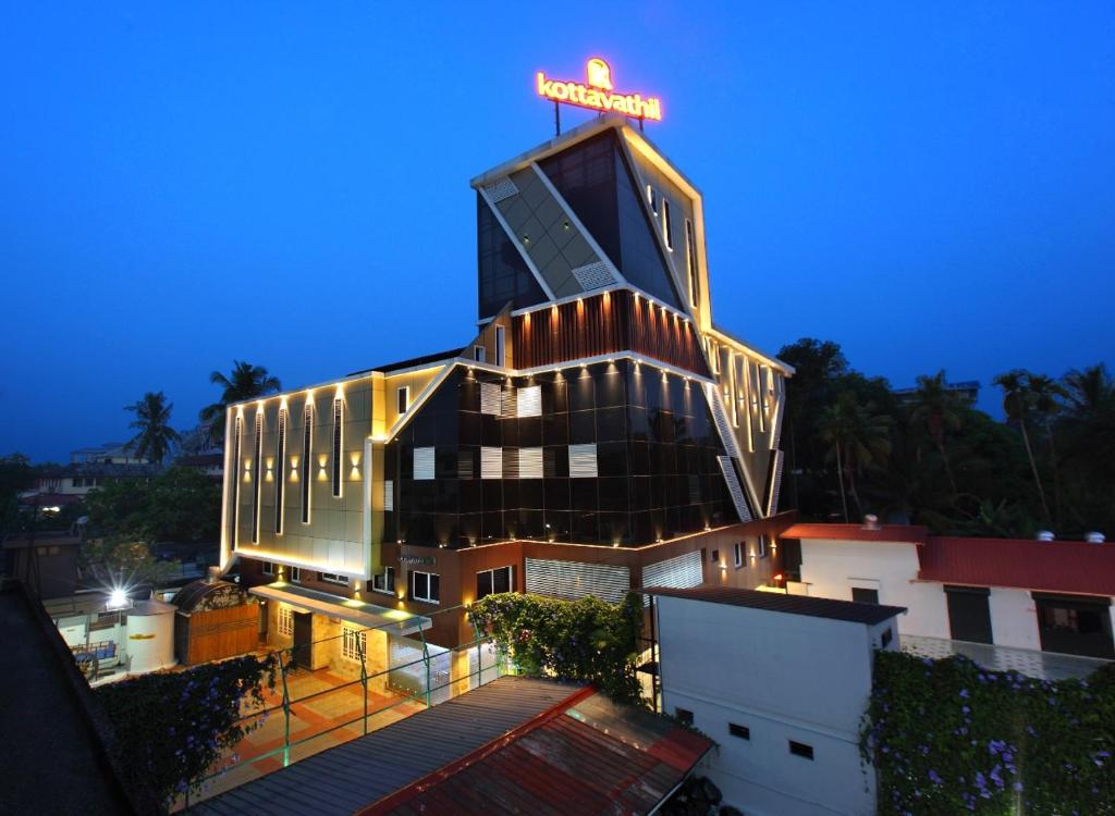 Un bâtiment avec un panneau de néon en haut. dans l'établissement Kottavathil Hotel, à Tripunittura