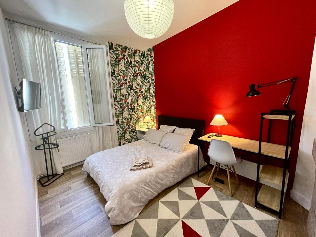 ein Schlafzimmer mit einer roten Wand, einem Bett und einem Schreibtisch in der Unterkunft La Terrasse du Colombier in Limoges